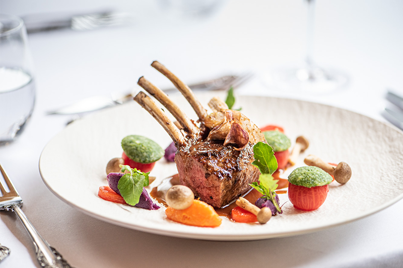 Agnello arrosto alla brace con erbe di montagna, patate al forno e verdure grigliate su piatto di terracotta