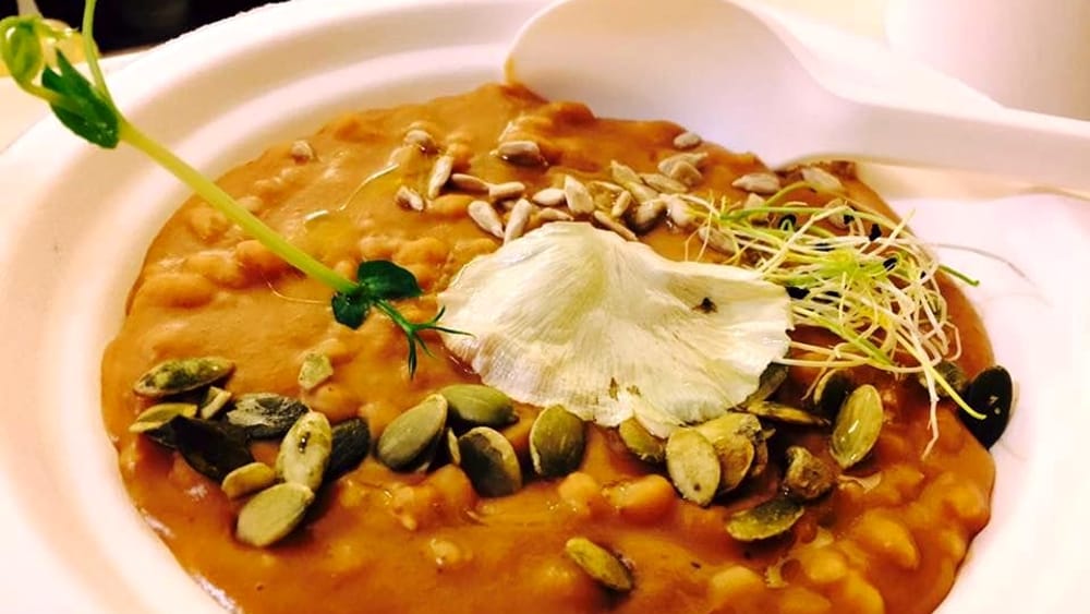 Zuppa di legumi misti servita in pentola di coccio con pane casereccio abbrustolito