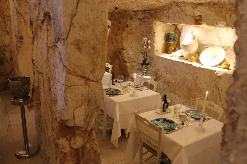 Angolo intimo con divano in pelle vintage e tavolino basso illuminato da lampada ad olio