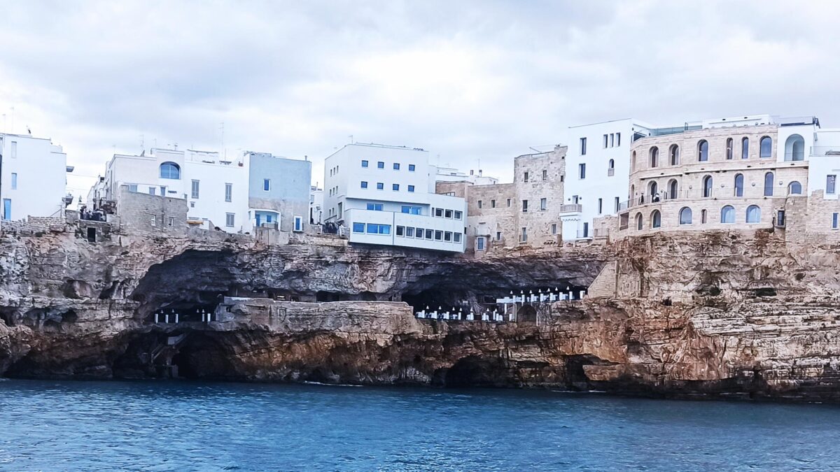 Camino monumentale in pietra con fuoco scoppiettante e pentole di rame appese