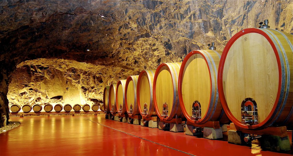 Cantina scavata nella roccia con bottiglie di vino invecchiate e luce soffusa